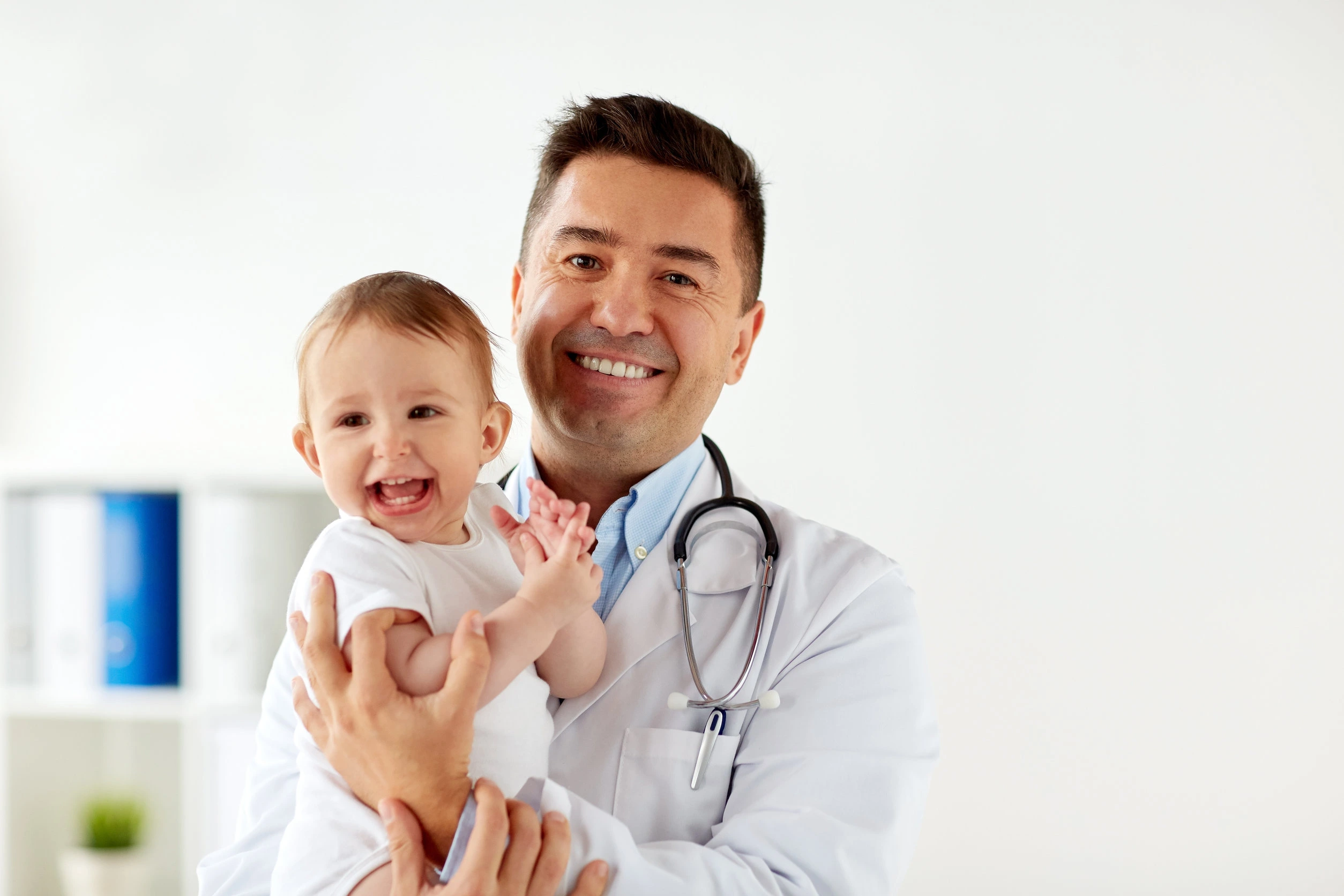 Physician holding an infant patient in a clinic office